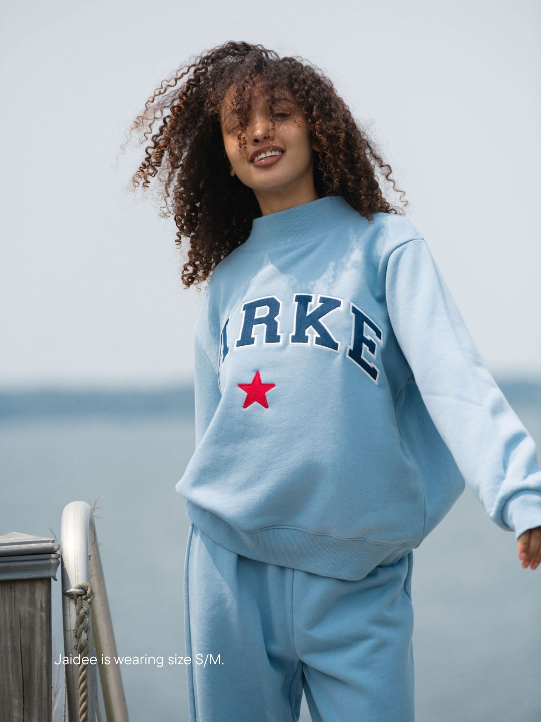 girl wearing coastal star varsity mockneck -sky