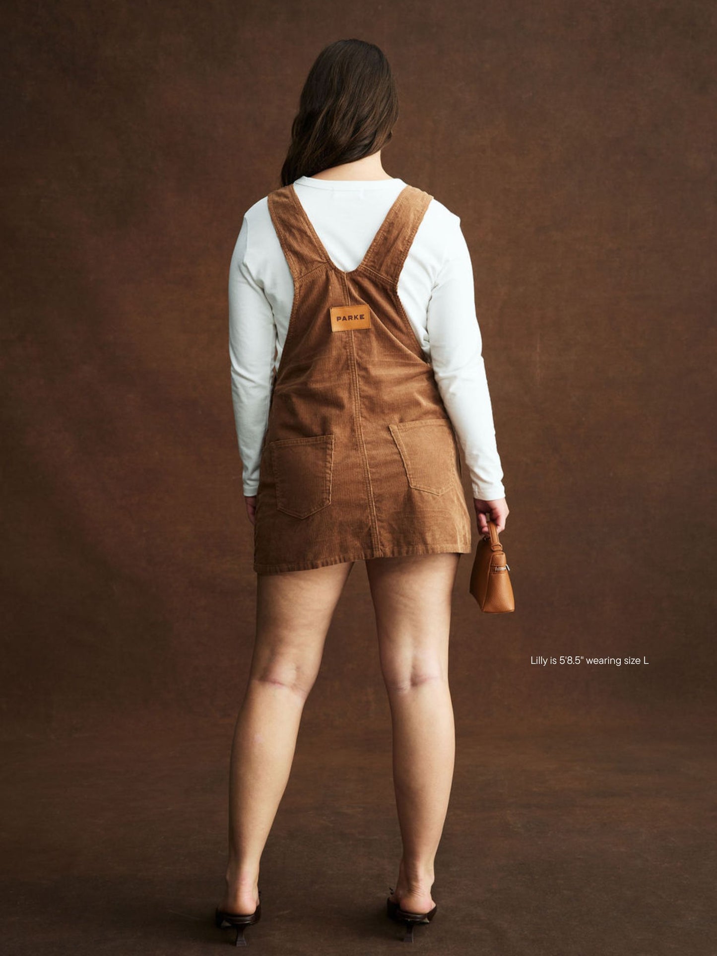 girl wearing Corduroy Overall Mini Dress -caramel corduroy