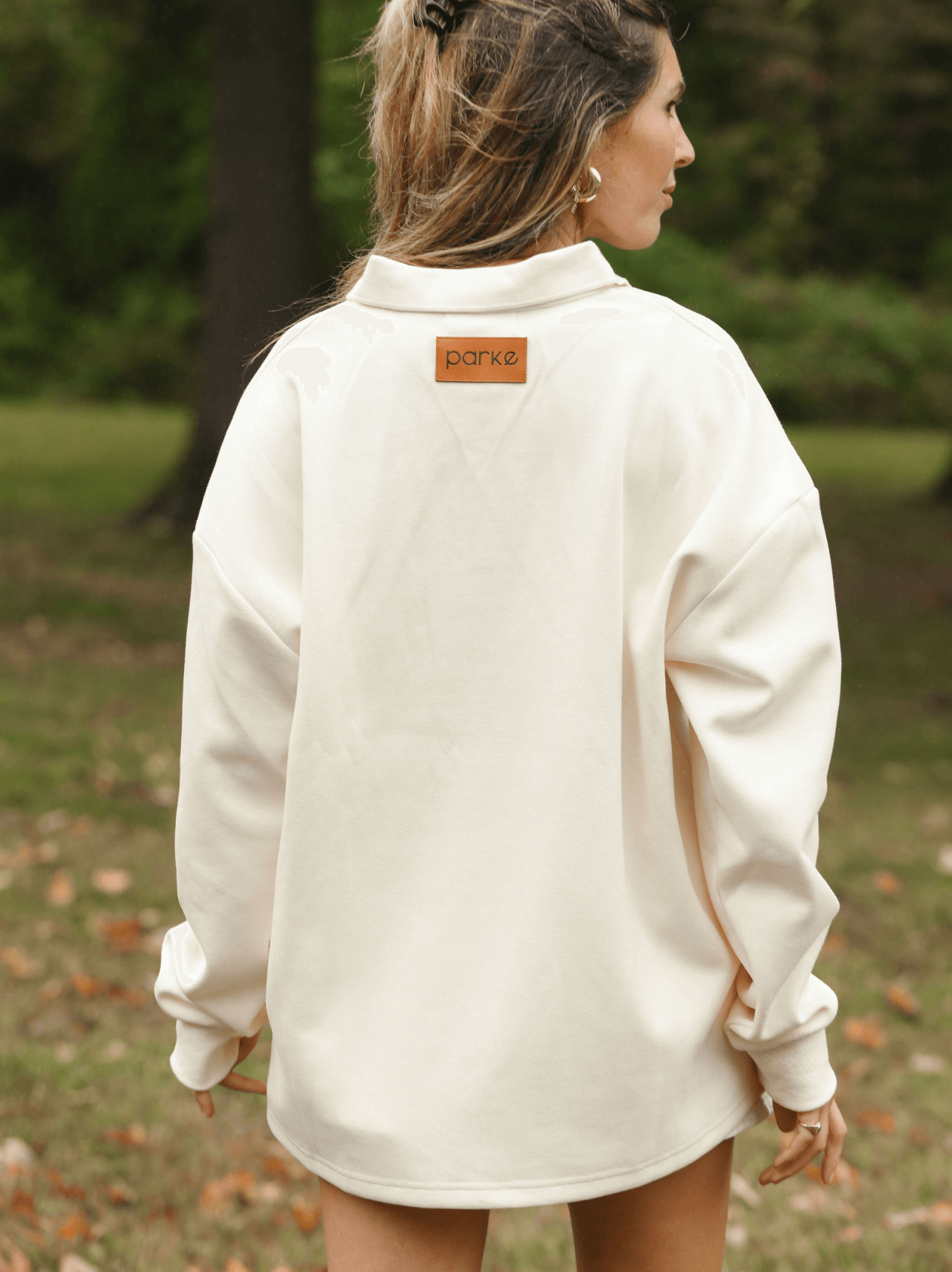 girl showing back patch of long sleeve polo - cream