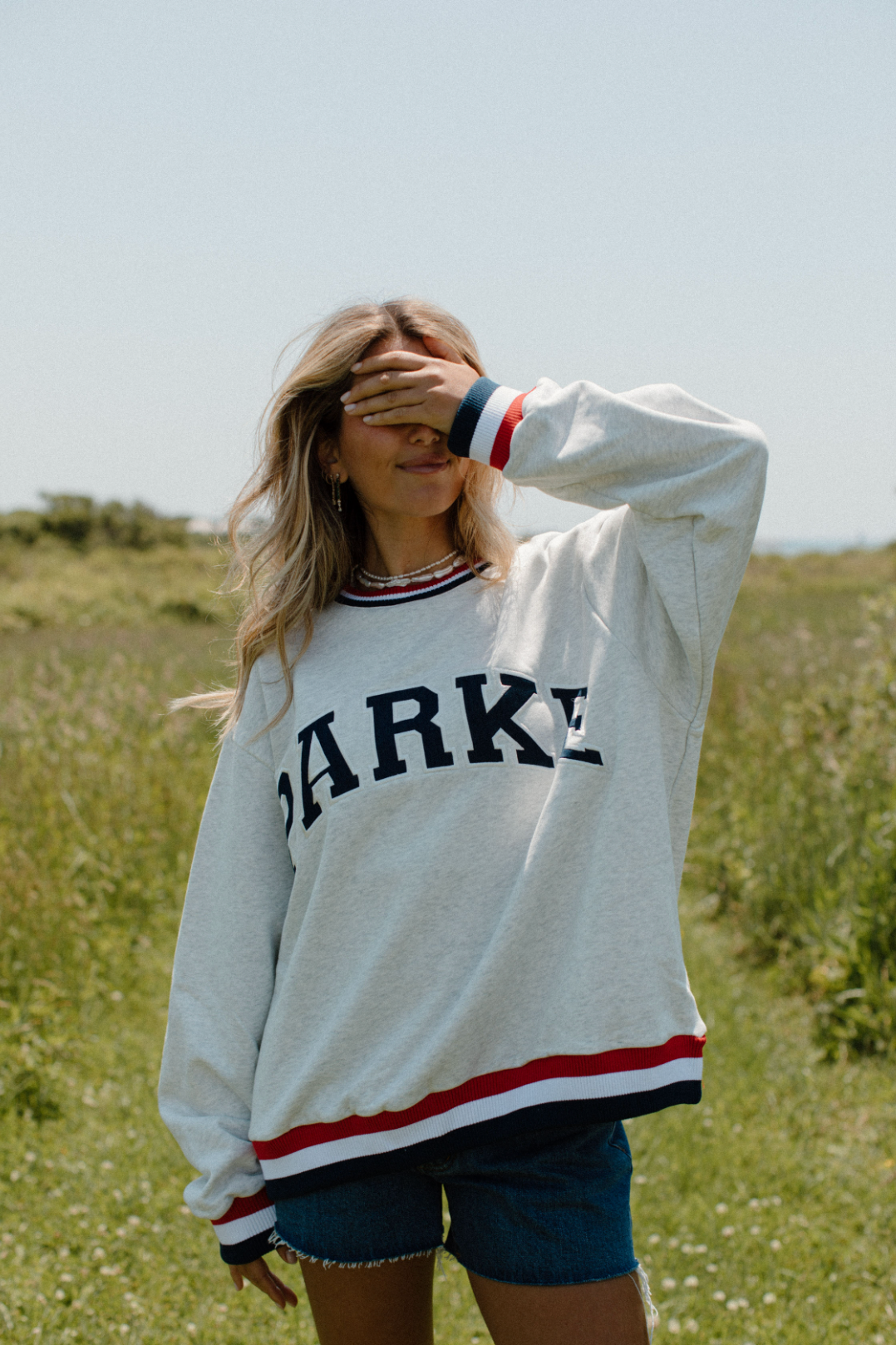 girl wearing washed grey + navy + red vintage varsity crewneck- washed grey + navy + red