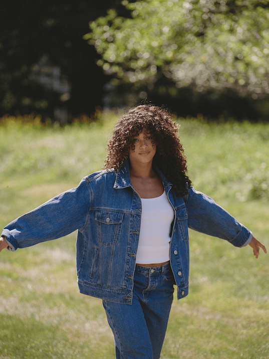 girl wearing med wash oversized jean jacket in a field -med wash