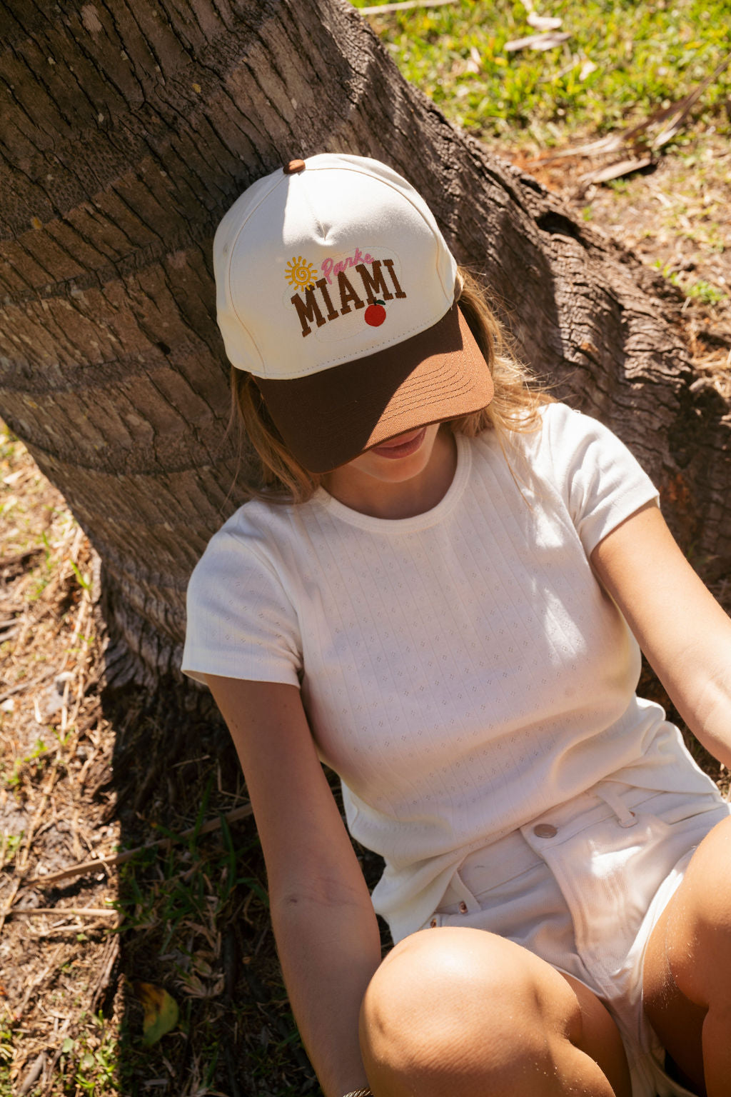 girl wearing Miami baseball hat flat lay -cream + chocolate brown